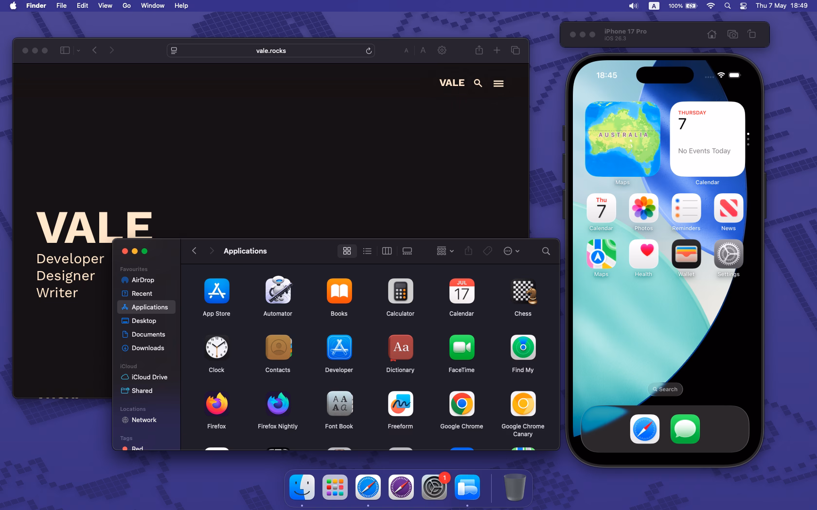 The rubtly rounded, sleek, blurred interface of macOS Sequoia. Vale.Rocks is open in Safari, the Applications folder is open in Finder, and a simulator is displaying an iPhone 17 Pro running iOS 26. Seen behind the apps is the dynamic Macintosh theme, in purple.